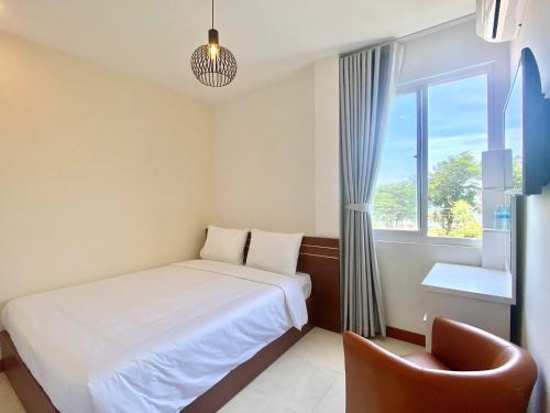 a bedroom with a bed and a window and a chair at Oasis Home in Nha Trang