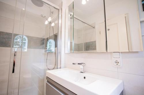a white bathroom with a sink and a shower at Haus Munkhoog in Munkmarsch