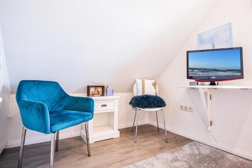 a living room with a blue chair and a tv at Haus Munkhoog in Munkmarsch