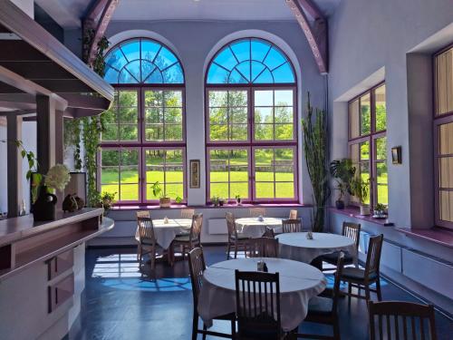 a restaurant with tables and chairs and windows at Hotel Melturi in Melturi