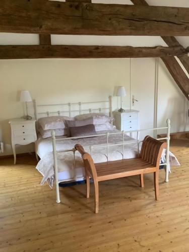 a bedroom with a bed and a wooden bench at Chambres d'Hôtes Belle Vallee in Domfront