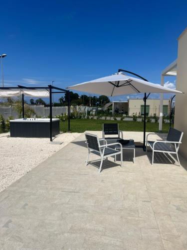 two chairs and an umbrella on a patio at Dionysus Luxury Villa in Brucoli