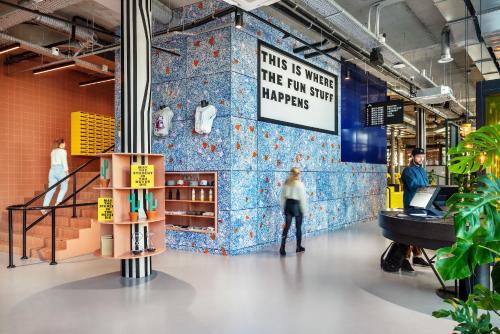 a person standing in a room with a wall with blue tiles at The Social Hub Delft Extended Stay in Delft