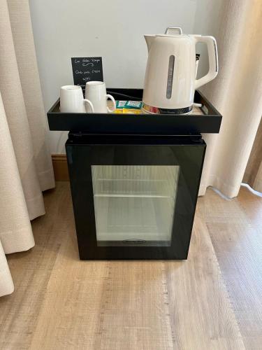 - une table noire avec une cafetière et des tasses dans l'établissement L'Hermione - Room in the heart of St Martin de Ré, à Saint-Martin-de-Ré