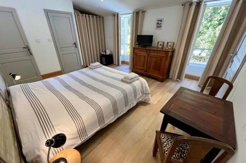 een slaapkamer met een bed, een tafel en een televisie bij L'Hermione - Room in the heart of St Martin de Ré in Saint-Martin-de-Ré