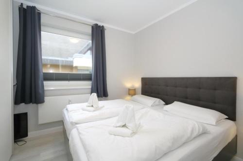 a bedroom with two white beds and a window at Haus Alice - Widlak 34/6 in Westerland