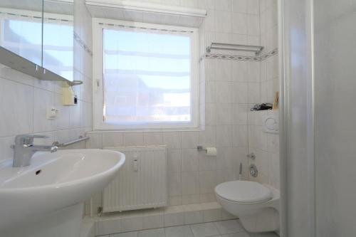a white bathroom with a sink and a toilet at Haus Alice - Widlak 34/6 in Westerland
