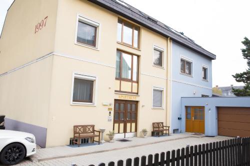 une maison blanche avec une voiture blanche garée devant elle dans l'établissement Donauauen Apartments, à Schwechat