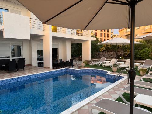 a swimming pool with chairs and an umbrella next to a building at Royal Villas in Dobra Voda