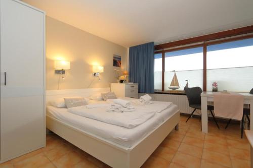 a bedroom with a large white bed and a table at Haus Sylter Welle 4-32 in Westerland (Sylt)