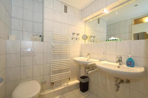 a bathroom with two sinks and a toilet and a mirror at Haus Sylter Welle 4-32 in Westerland (Sylt)