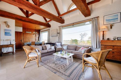 un salon avec un canapé, des chaises et une table dans l'établissement Grande maison face à l'océan avec jardin pour 11, à Saint-Pabu
