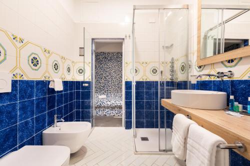 a blue tiled bathroom with a toilet and a sink at YourHome - Lidia Rooms & Suites in Sorrento
