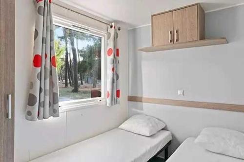 une petite chambre avec deux lits et une fenêtre dans l'établissement Camping 3 étoiles - Piscine - efcagd, à Saint-Georges-de-Didonne