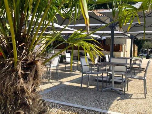 un groupe de chaises et de tables devant un bâtiment dans l'établissement Camping 3 étoiles - Parc aquatique - efcafh, à Saint-Mandé-sur-Brédoire