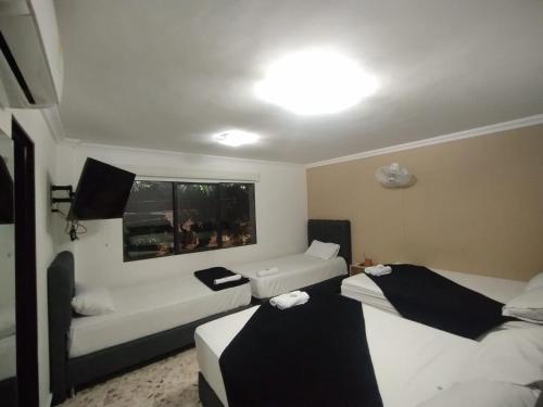 a room with two beds and a couch and a window at Hotel De León Estadio in Medellín