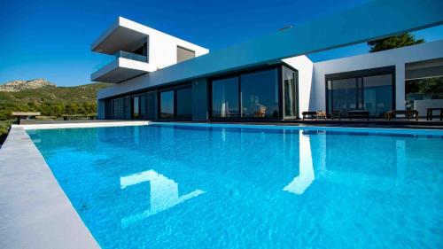 a large swimming pool in front of a house at Villa Scorpios with private pool in Áyioi Apóstoloi