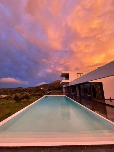 a swimming pool in front of a building with a sky at Villa Scorpios with private pool in Áyioi Apóstoloi