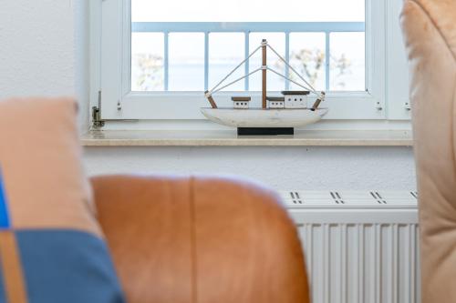 a model boat sitting on a window sill next to a chair at Villa Fördestrand Fender in Laboe