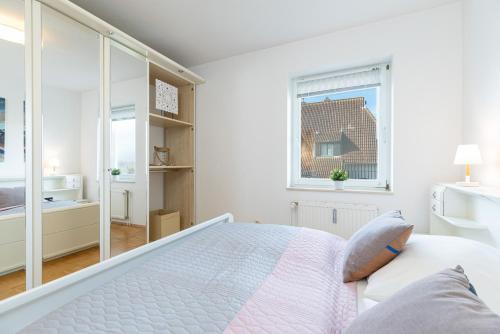a white bedroom with a bed and a window at Villa Fördestrand Fender in Laboe