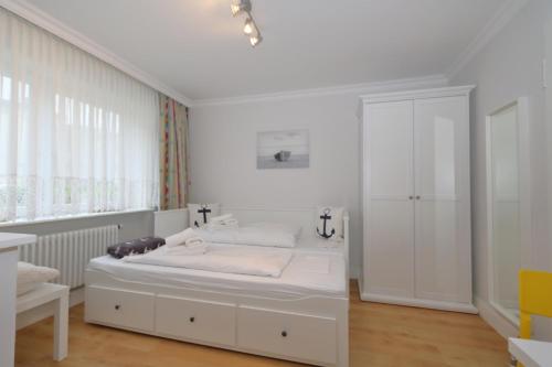 a white bedroom with a bed and a window at Haus sarah 08 in Westerland