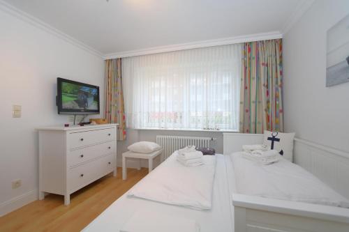a white bedroom with two beds and a tv at Haus sarah 08 in Westerland