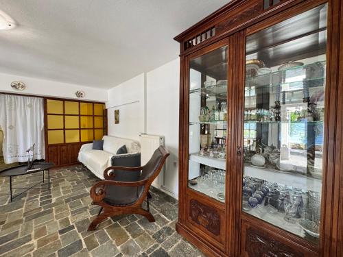 a room with a chair and a cabinet with glass doors at Kerveli Coast in Samos
