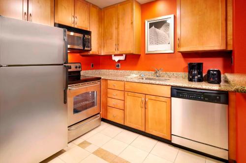 a kitchen with stainless steel appliances and wooden cabinets at Residence Inn East Rutherford Meadowlands in East Rutherford