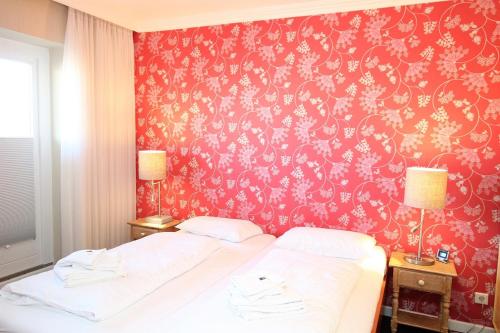 a bedroom with a bed with a red wall at App. Hussmann 8/17 in Westerland (Sylt)
