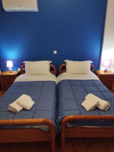 two beds in a room with blue walls at Joel Apartment in Pefkali
