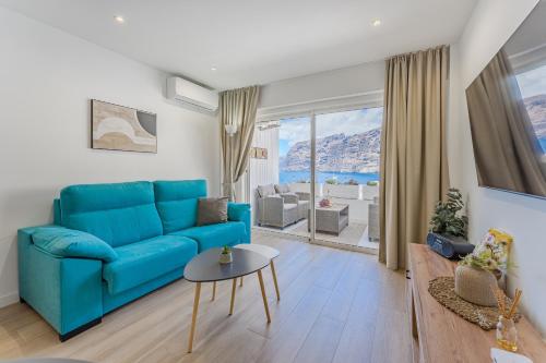 un salon avec un canapé bleu et une table dans l'établissement Vista Magica Beachfront Suite, à Acantilado de los Gigantes