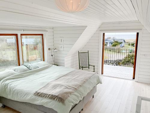 a white bedroom with a bed and a large window at Charming House by the Sea with Beautiful Garden in Glommen