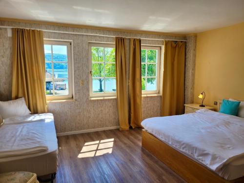 a hotel room with two beds and two windows at SEE-Hotel Seeschau - direkt am Bodenseeufer in Reichenau