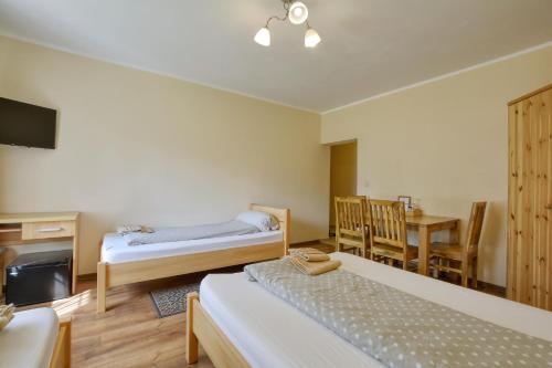 a room with two beds and a table and a desk at SkiBike House Stronie Śląskie in Stronie Śląskie