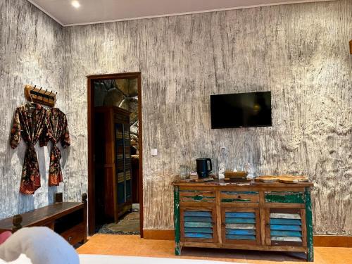 a room with a wooden dresser and a television on a wall at Royal Amertha Ubud Jungle View in Gianyar