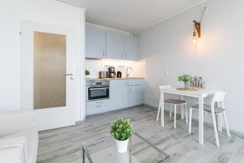 a white kitchen with a white table and a white couch at Marina Wendtorf Kajüte in Wendtorf