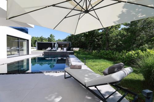 a patio with an umbrella next to a swimming pool at Luxury Villa Cloer, Jadranovo - Sauna,Steam room, 2 Jacuzzis in Jadranovo