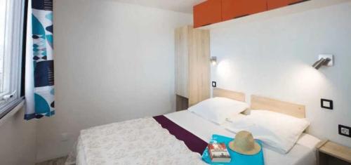 カネ・アン・ルシヨンにあるCamping 4 étoiles - Piscine - ccaaeagの帽子が置かれたトレイが置かれたベッドのある寝室