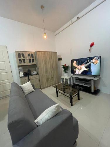 a living room with a gray couch and a tv at Deluxe studio unit at Modena Town Sq in Tunghaan