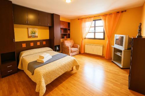a bedroom with a bed and a chair and a television at Apartamento Casa Pilar in Ribadesella
