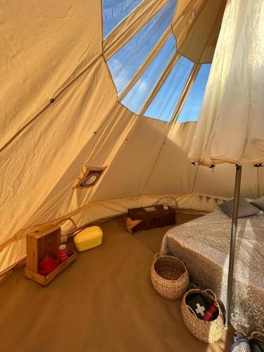 a tent with a bed and baskets in it at Luxury Glamping - Heydaze in Lostwithiel