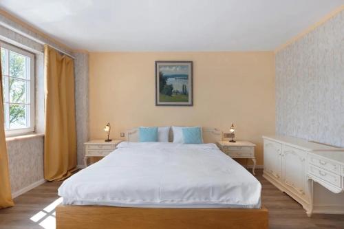 a bedroom with a large white bed and two tables at SEE-Hotel Seeschau - direkt am Bodenseeufer in Reichenau