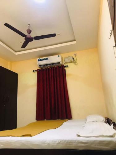 a bedroom with a ceiling fan and a red curtain at Crown palace tourist home in Ernakulam