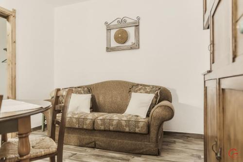 a couch in a living room with a clock on the wall at S'Arrosa de Monti in Villaputzu