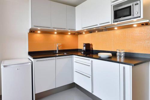 une cuisine avec des armoires blanches et un micro-ondes dans l'établissement Appartement CRAZY - Port Ambonne PA335 - 2 personnes, au Cap d'Agde