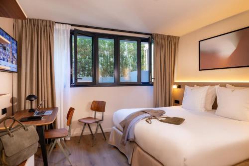 ein Hotelzimmer mit einem Bett, einem Schreibtisch und einem Fenster in der Unterkunft Yuna Montmartre - ApartHotel in Paris