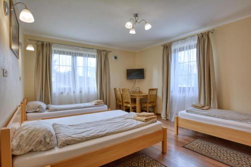 a bedroom with two beds and a table and chairs at SkiBike House Stronie Śląskie in Stronie Śląskie