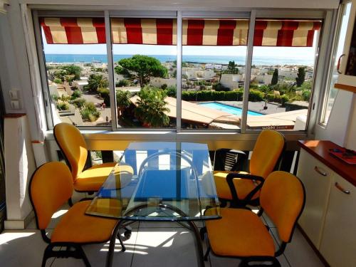 une salle à manger avec une table et des chaises en verre ainsi qu'une fenêtre dans l'établissement Appartement NAUTIC - Port Nature PN583 - 2 personnes, au Cap d'Agde