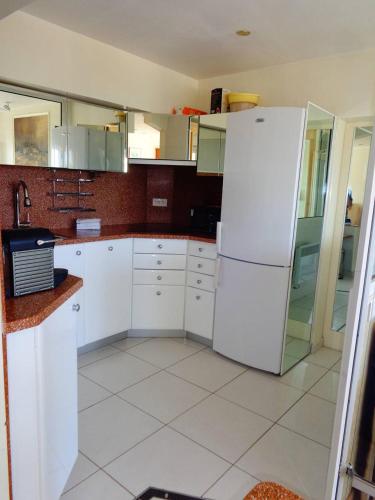 une cuisine avec des armoires blanches et un réfrigérateur blanc dans l'établissement Appartement NAUTIC - Port Nature PN583 - 2 personnes, au Cap d'Agde