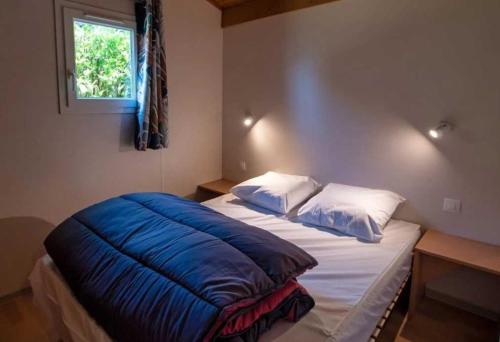 - un lit avec une couverture bleue dans l'établissement Chalet 3 étoiles - ccaaafc, à Sorèze